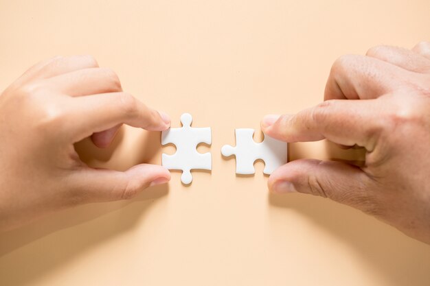 hand connecting puzzle pieces on table