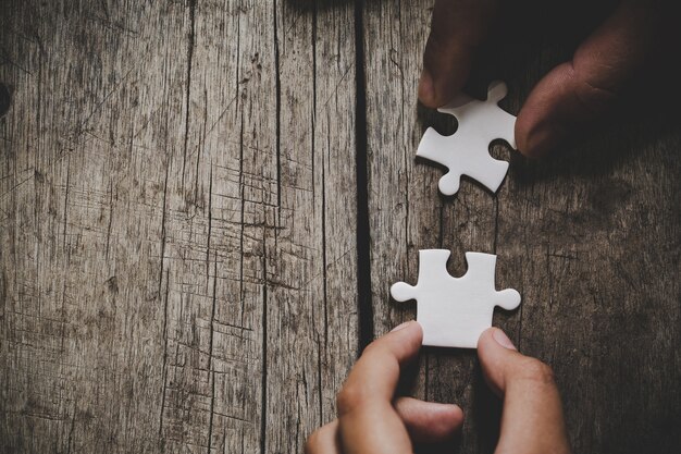 hand connecting puzzle pieces on table 