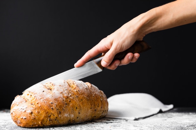 Hand cutting bread loaf with knife