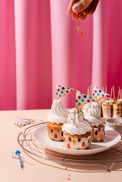 Hand decorating cupcakes with colorful sprinkles