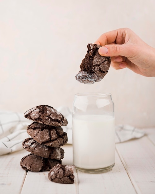 Hand dipping chocolate cookie in milk