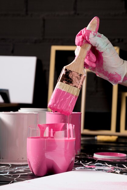 Hand dipping paint brush in pink paint