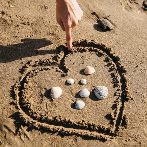 Hand drawing heart in the sand