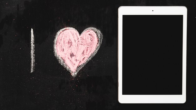 Hand drawn alphabet I and heart shape near digital tablet on chalkboard