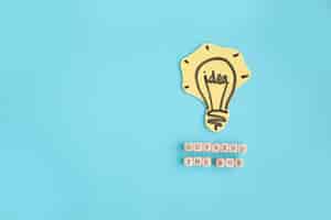 Free photo hand drawn idea light bulb outside the box text made with blocks on blue background