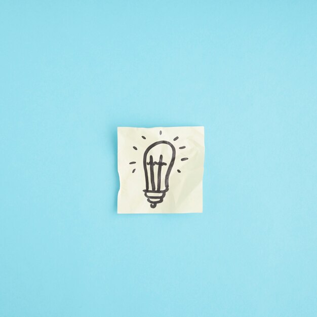 Hand drawn light bulb on the crumpled paper against the blue background