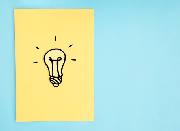 Hand drawn light bulb on yellow paper over the blue background