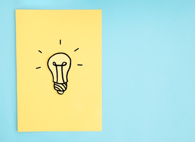Hand drawn light bulb on yellow paper over the blue background