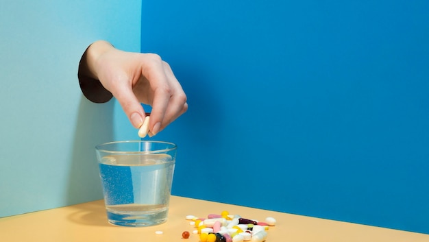 Free photo hand dropping effervescent tablet in glass of water