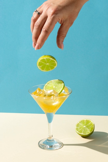 Hand dropping lime slice into cocktail