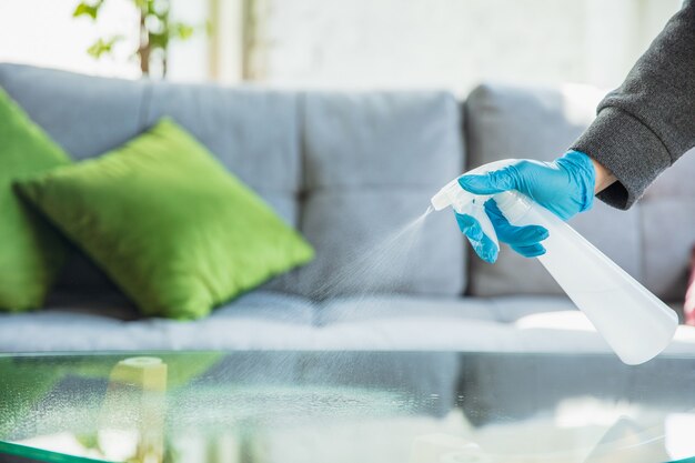Hand in gloves disinfecting surfaces with sanitizer at home