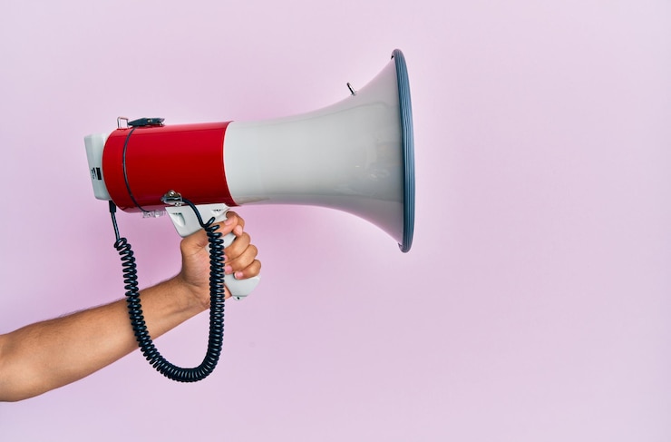 Free Photo hand of hispanic man holding megaphone over isolated pink background.