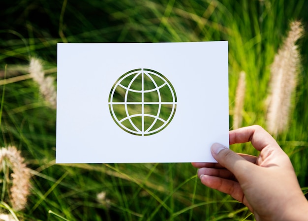 Free photo hand hold globe paper carving with grass background