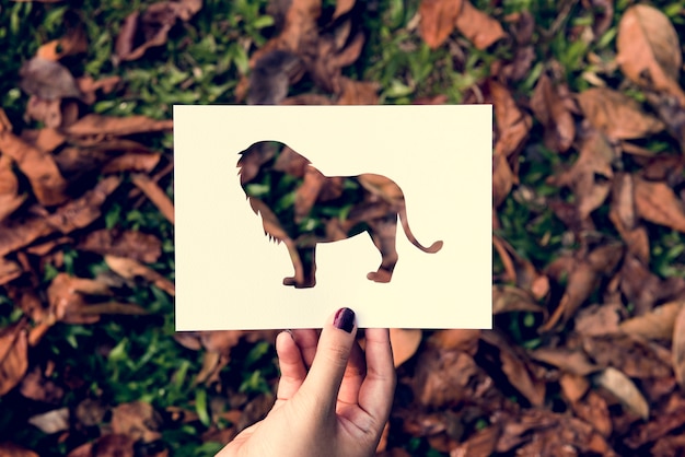 Free photo hand hold lion paper carving with grass background