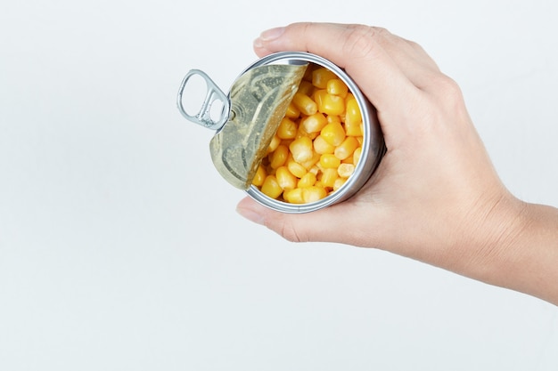 Бесплатное фото Рука консервную банку вареной сладкой кукурузы.