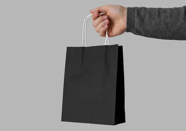 Free photo hand holding black paper bag