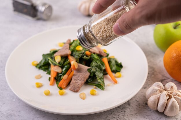 Hand holding a bottle of white sesame pouring food.