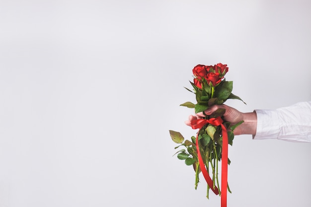 Free photo hand holding a bouquet of roses