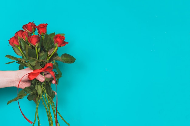 Free photo hand holding a bouquet of roses