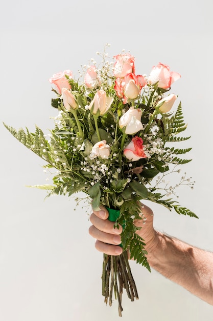 Free photo hand holding bouquet of roses