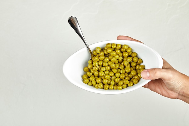 Hand holding a bowl of boiled green peas.