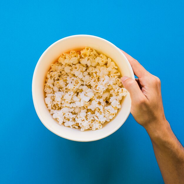 Hand holding bucket of popcorn