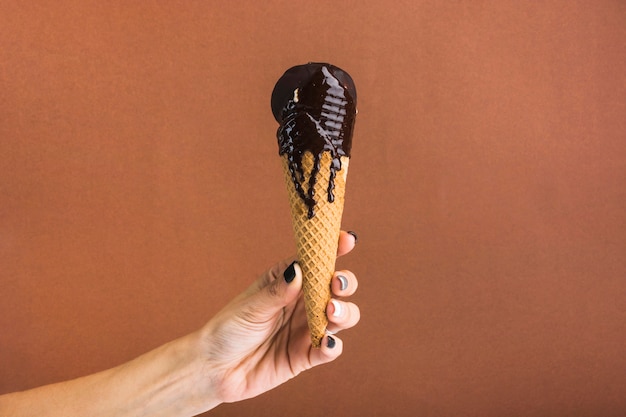 Foto gratuita mano che tiene il gelato al cioccolato