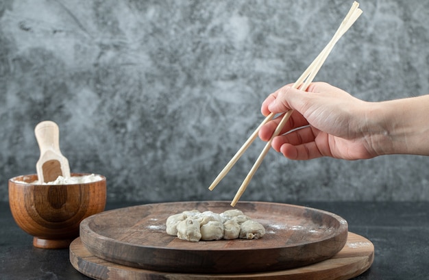 Hand holding a chopstick with a dumpling.