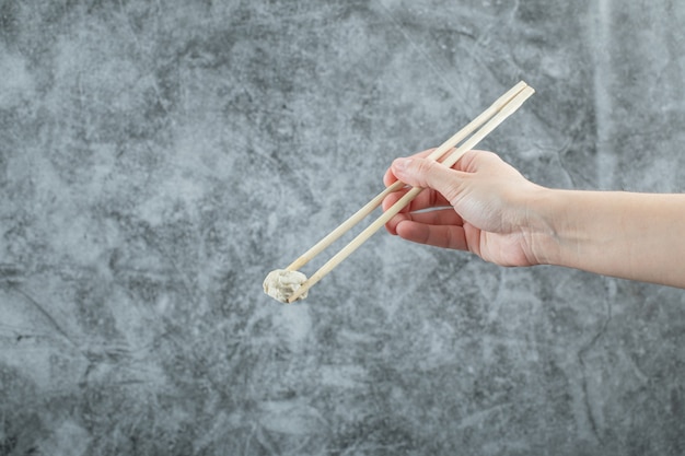 Free photo hand holding a chopstick with a dumpling.