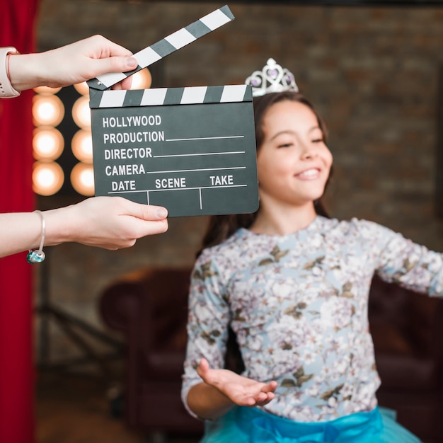 Hand holding clapper board in front of girl performing in studio