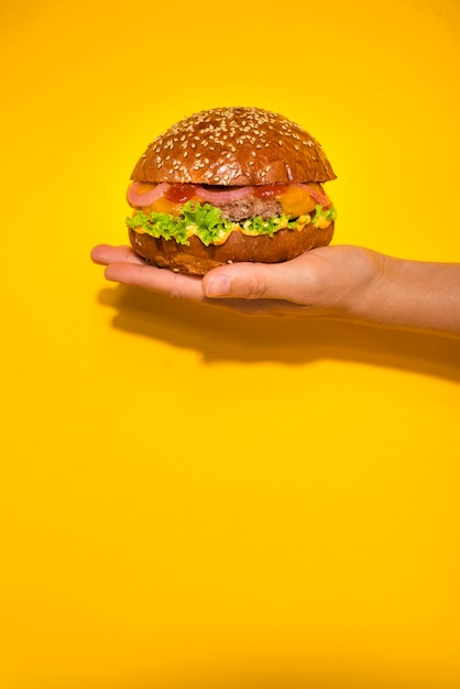 Hand holding classic beef burger with lettuce