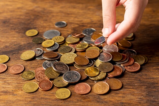 Hand holding a coin from a pile high view