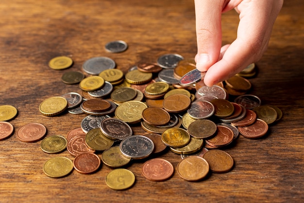 Hand holding a coin from a pile high view