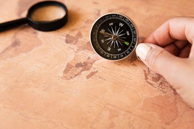 Hand holding a compass on a map