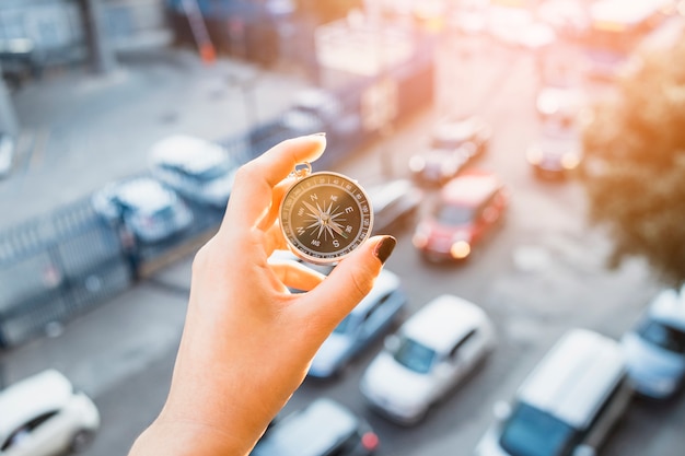 Hand holding compass above street with cars