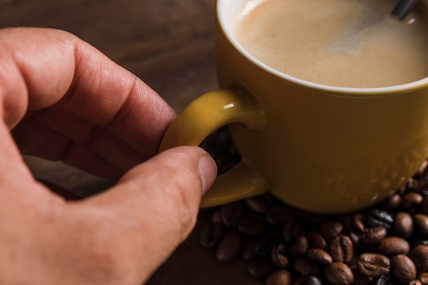 Hand holding cup handle with coffee