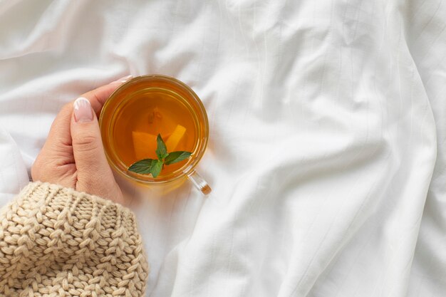 Hand holding cup of tea with mint