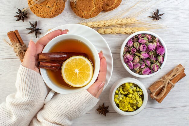 Hand holding a cup with black tea with cinnamon