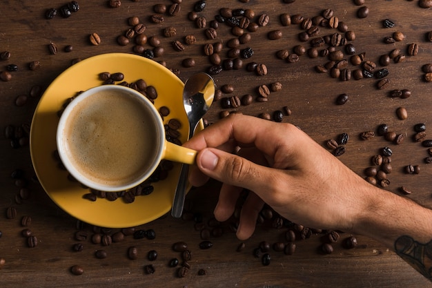 Hand holding cup with coffee near plate