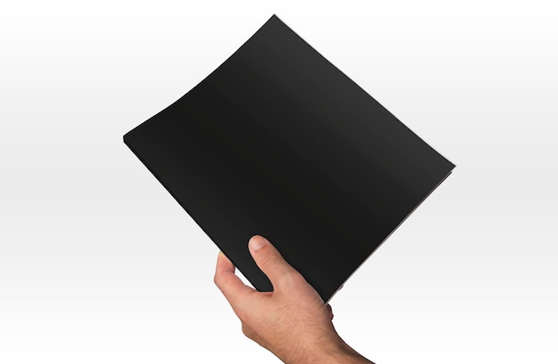 Free photo hand holding a dark magazine on a white background