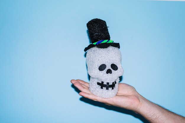 Hand holding decorative skull in hat