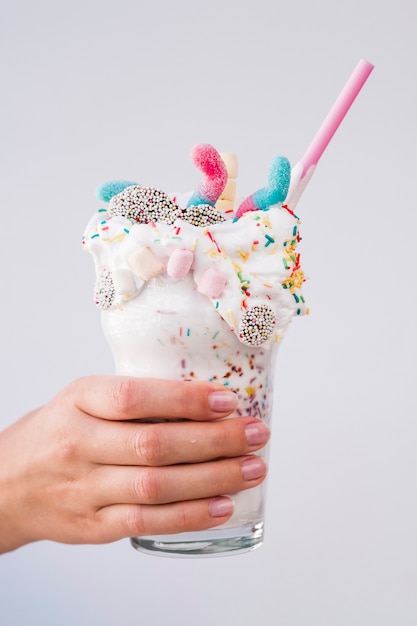 Hand holding a delicious milkshake with plain background