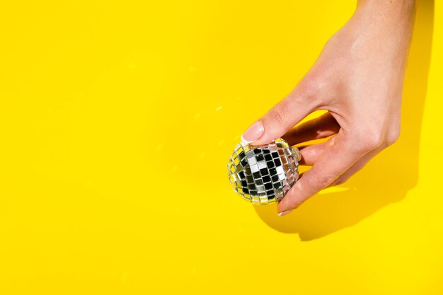 Free photo hand holding disco globe with copy space