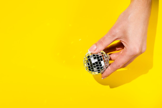 Hand holding disco globe with copy space