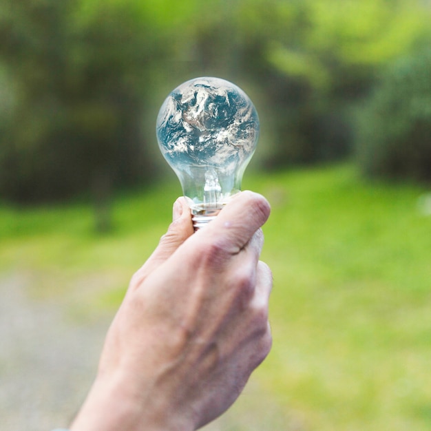 Free photo hand holding earth in glass lamp