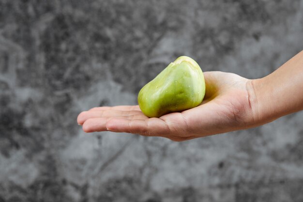 Hand holding a fig on marble.