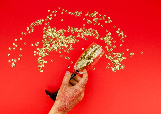 Hand holding glass with gold glitter