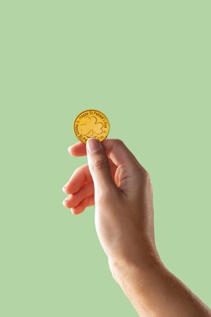 Рука держит золотую монету ул. концепция дня патрика