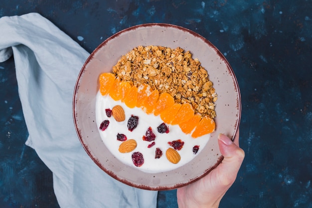 Free photo hand holding granola fruit bowl