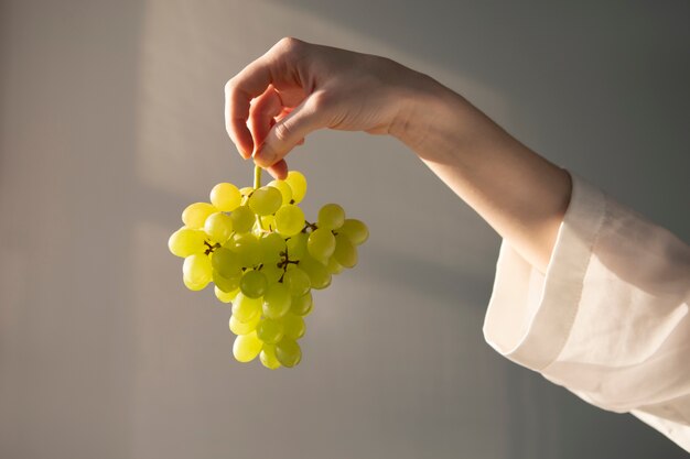 Hand holding green grapes summertime